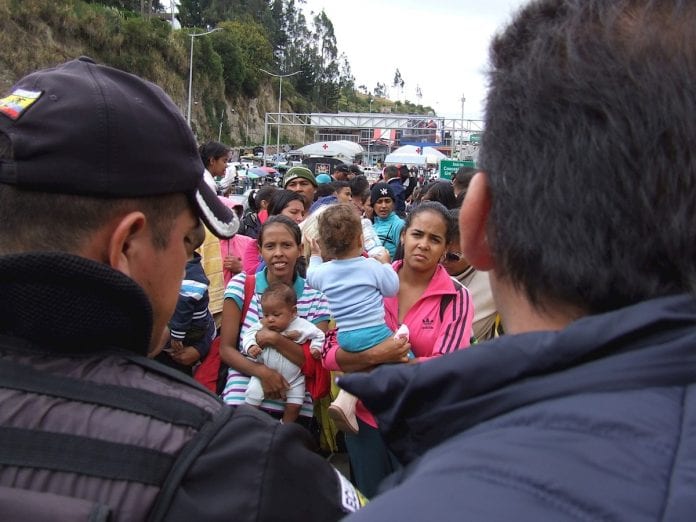 Se ven familias venezolanas, frente a autoridades policiales, a la espera de poder cruzar la frontera y entrar a Ecuador desde el Paso de Rumichaca